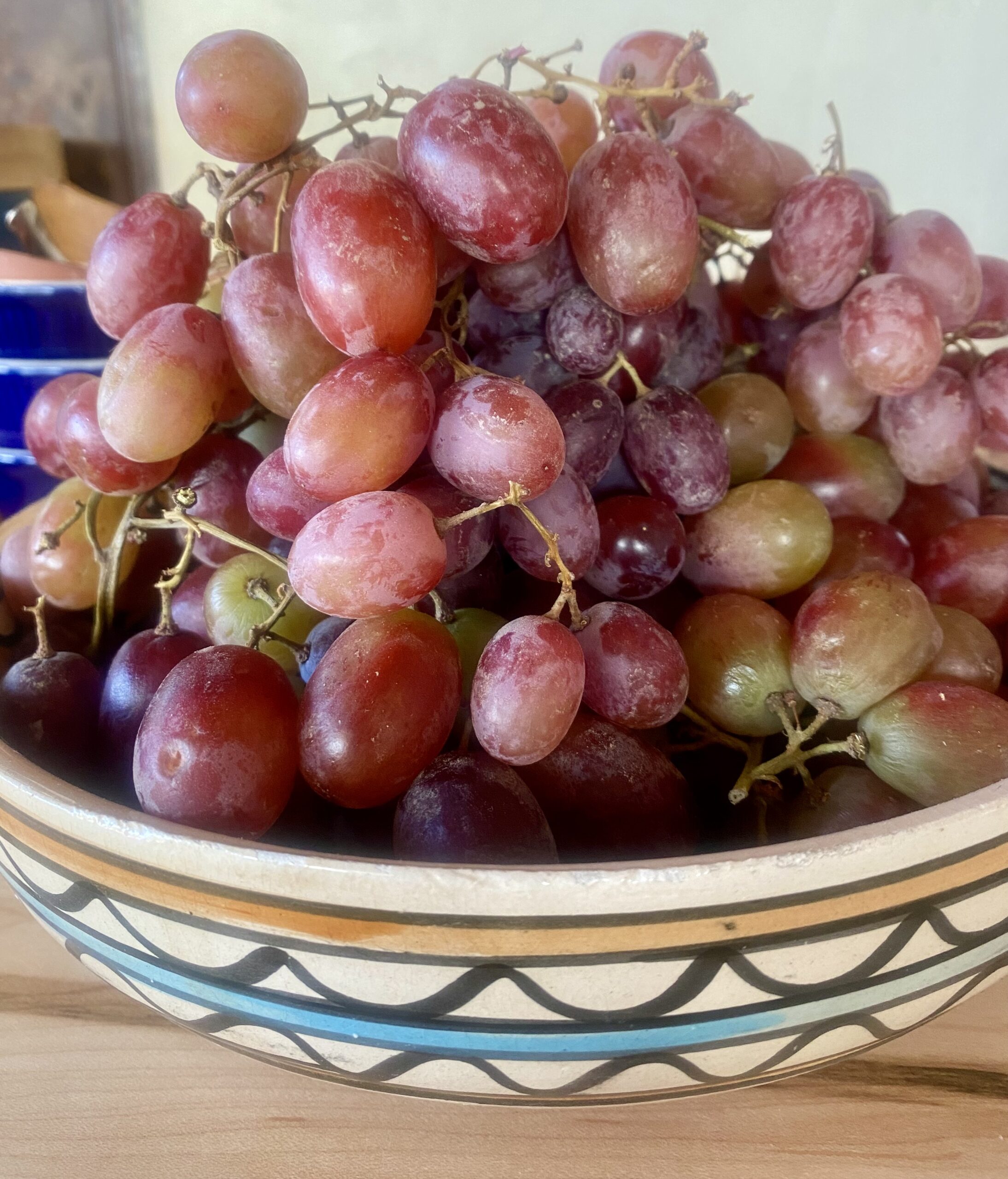 a pile of purple grapes in a ceramic bowl