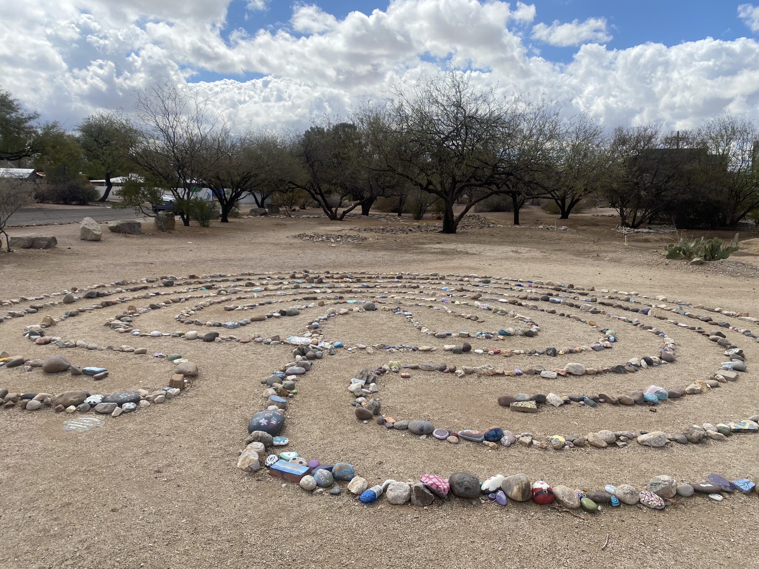 a desert labyrinth made from small stones, clouds in a blue sky